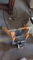 Full view of Tacx bike trainer mount standing on a concrete floor, showing orange and gray frame with Tacx logo.