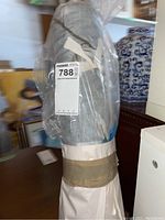 Full bolt of gray polyester fabric with leaf pattern wrapped in plastic.