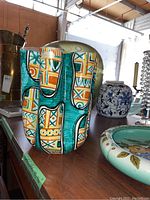 Photo showing painted vase with geometric pattern, blue and white Asian vase, and other pottery items