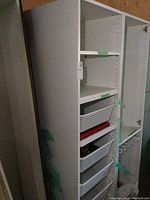 Full view of tall white melamine cabinet with three slide-out baskets and open shelving above. The cabinet appears tall with clean white finish.