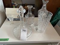 Image showing three crystal decanters with one stopper on. Two stoppers separate, one does not fit. Clear cut crystal surface.