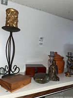 Wide view of various decorative items including candle holder, wooden boxes, figurines, and ceramic jar on a shelf