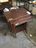 Stacked view showing the three wooden nesting tables of varying sizes with brass claw feet.