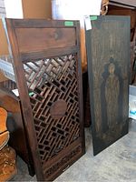 Two wooden items: carved privacy screen and religious panel side by side on floor.