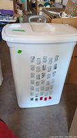 White rectangular plastic laundry hamper with ventilation holes, closed lid with gray pull handle, and wheels visible underneath.