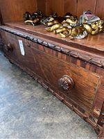 Close-up view of the bottom drawer front showing carved wooden flower knob and wood grain.