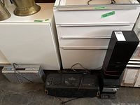 Photo of Sony Micro Hi-Fi system, LXI boombox, and Sony VHS player on floor near white drawers.