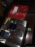 Photo shows heavy silver necklace and various earrings and rings in a tin box and on a red surface.