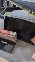 Sharp Aquos 46 inch TV leaning against a cart, detached TV stand and original mount box visible on ground