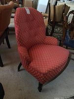Side angle view of vintage upholstered chair showing patterned fabric, cushioned seat, and wooden legs with casters