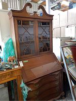 Front view of the full secretary desk showing the spiral top, glass doors, drop-front desk, and curved drawers below.