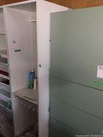 Tall white melamine wardrobe cabinet with open interior showing hanging rod and shelves.