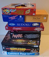 Stacked view showing boxes of Uno Spin, Trivial Sense Cards, Sudoku, Scrabble, Manial Electronic Game, Deal or No Deal Electronic Game, Battleship, Connect Four