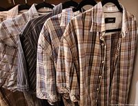 Four men's XL short sleeve plaid button-up shirts by J Campbell Los Angeles hung on hangers and displayed together