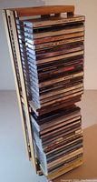 Side view of vertical stacked CDs showing varied artists and titles inside a wooden crate with slats and light finish