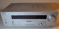 Full front view of silver Sony AV receiver showing the power button, digital display, various controls including input selection and volume dial.