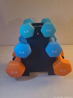 Front view of the dumbbell set with 3 lbs, 5 lbs, and 8 lbs neoprene hex dumbbells on the rack stand.