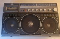 Front view of boom box showing three speakers, cassette compartment, and control panel.