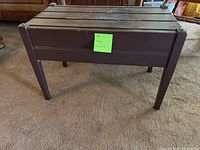 Brown wooden folding table with slatted top and four legs on carpet.