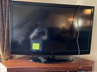 Front view of 42-inch flat screen TV with remote placed on stand.