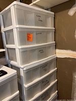 Photo showing a stack of white plastic storage bins with three drawers each, drawer fronts semi-transparent with labels such as Candy, Plastic Containers.