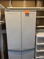 Photo of closed white louvered double doors of plastic storage closet cabinet.