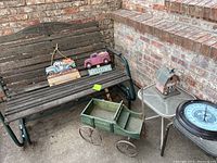 Wide shot of porch bench with decorative items and wagon on concrete porch slab against brick wall.