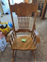 Front view of wooden rocking chair showing carved backrest, spindle back, and seat.