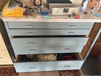 Metal workbench with four drawers, some drawers partially open illustrating contents.