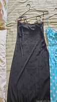 Black sleeveless evening gown with embroidered floral pattern on bed