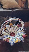 Ceramic basket with floral design, multicolor with red, yellow, blue, and green flowers, petal-shaped edges, and a top handle, glossy finish.