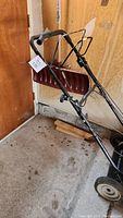 Mastercraft lawn mower with handle and attached red plow blade against wooden wall