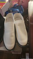 White pair of men's leather slip-on shoes shown from top, showing smooth surface and rounded toe shape.