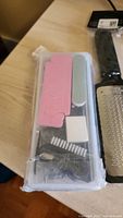 Clear plastic case with pink toe separator, nail files, small brush, and cotton pads inside, unopened.