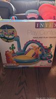 Front view of the unopened box of Intex Dinoland Play Center inflatable kids pool with colorful dinosaur themed design shown on packaging.