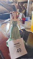 Front view of Royal Doulton Emerald Lady figurine showing red-haired lady in emerald green dress standing on a base with auction tag.