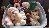 Plastic storage bin filled with assorted stuffed animals including Minnie Mouse, pink elephant, green character, and teddy bears.