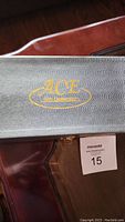 Closed black case with gold ACE logo on top.