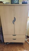 Closed wardrobe showing two doors with curved handles and two drawers below.