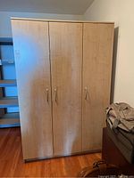 Full view of the MDF laminate closet cabinet showing three door fronts and light wood finish.