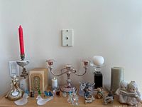 Full display of crystal swan figurine, miniature glass figures, Hummel figurines, candles, and candelabra on wood surface against white wall.