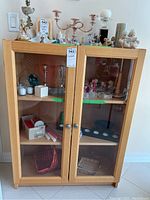Front view of the IKEA Billy glass door cabinet with various items inside and on top, showing the wooden frame and glass panels.