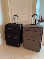 Photo of two Samsonite wheeled suitcases side by side, one black and one brown, showing overall size and design