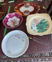 Four decorative platters and four glass swizzle sticks arranged on a table, top-down view.