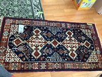 Photo of small wool rug showing full pattern and borders, cut-off fringes