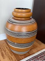 Full side view of the large ceramic pot showing its size, shape, color, and textured horizontal stripes.