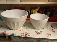 Two white/off-white ceramic mixing bowls with fluted sides shown from front