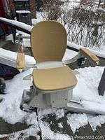 Front view of beige Acorn stairlift seat mounted on 75-inch rail in snow