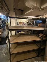 Black industrial metal shelving unit with five shelves in a basement setting, showing unit height, width, and shelf depth.