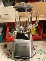 Full view of Black & Decker blender with glass jar and lid on top of patterned tablecloth, showing the full appliance.